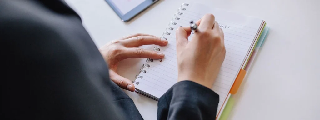 Person macht sich strukturierte Notizen in einem Notizbuch während eines beruflichen Trainings und unterstützt damit die effiziente Planung eines Seminars.