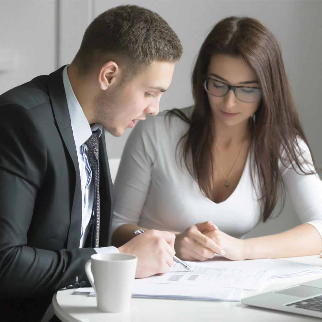 Zwei Kollegen besprechen gemeinsam Unterlagen und zeigen klare, strukturierte Kommunikation im Rahmen einer professionellen Mitarbeiterschulung.