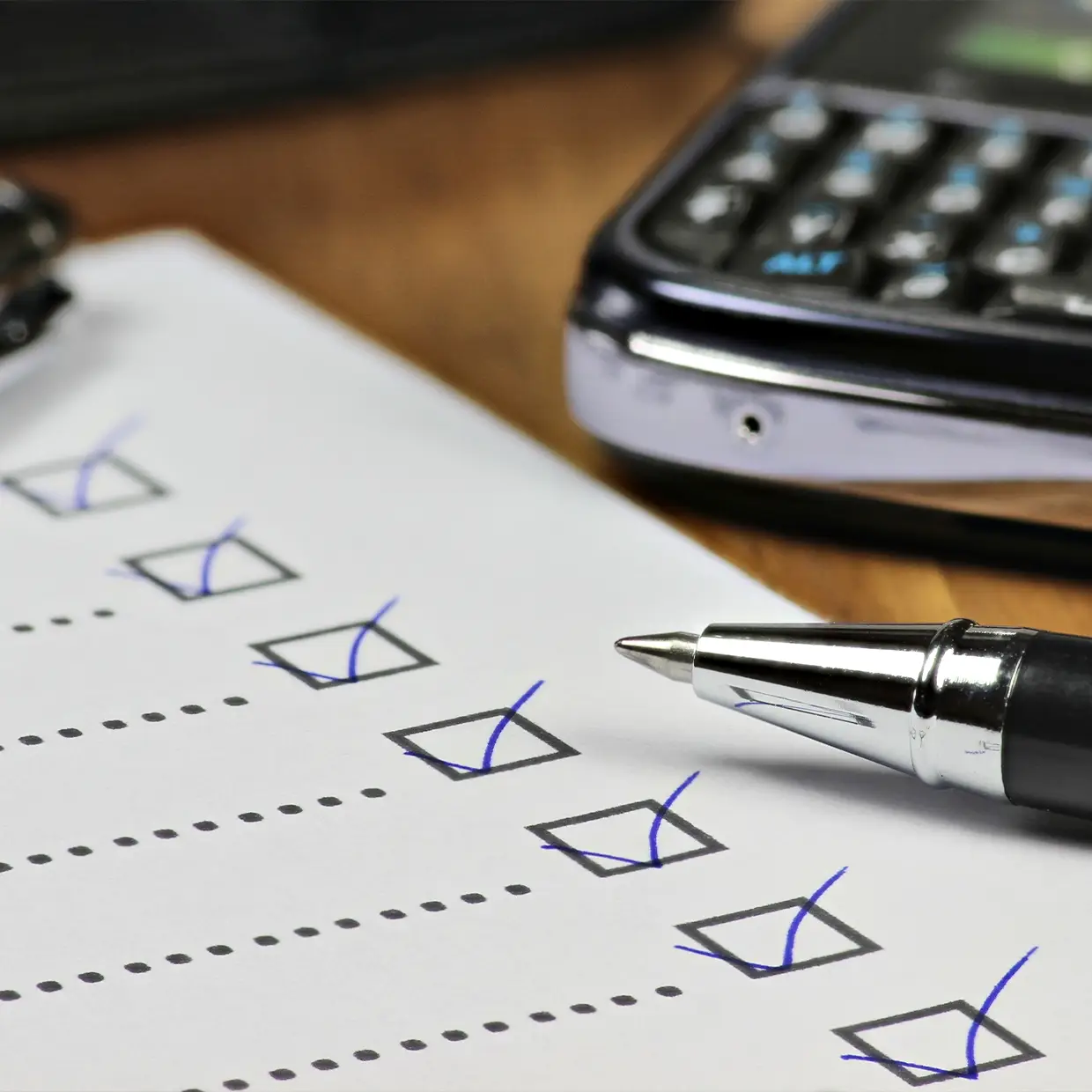 Ausgefüllte Checkliste mit Häkchen und Kugelschreiber auf einem Schreibtisch, symbolisiert strukturierte Vorbereitung im Rahmen eines professionellen Mystery Checks.