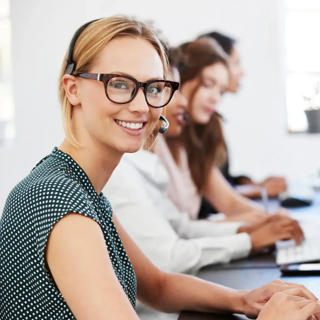 Freundliche Mitarbeiterin im Callcenter führt ein professionelles Telefonat und zeigt souveräne Kommunikationsfähigkeit im Rahmen eines modernen Telefontrainings.