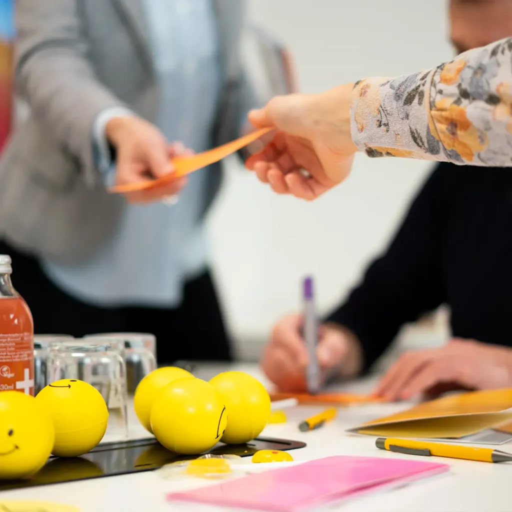Teilnehmende übergeben sich eine gelbe Karte während eines Coaching-Workshops von Smiling Customer.