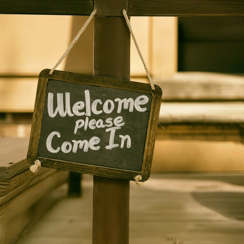 Kleines Willkommensschild mit der Aufschrift ‚Welcome, please come in‘ zeigt einen herzlichen Empfang und symbolisiert gelebte Servicequalität Hotel.
