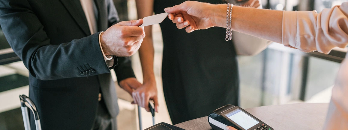 Hotelgäste überreichen ihre Kreditkarte an die Rezeptionistin beim Check-in und erleben einen professionellen Empfang im Rahmen eines Front Office Checks.